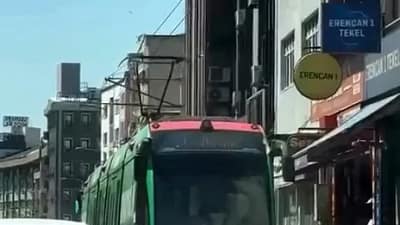 Bursa’da seyir halindeki tramvayın arkasına tutunarak yolculuk yapan iki çocuk,